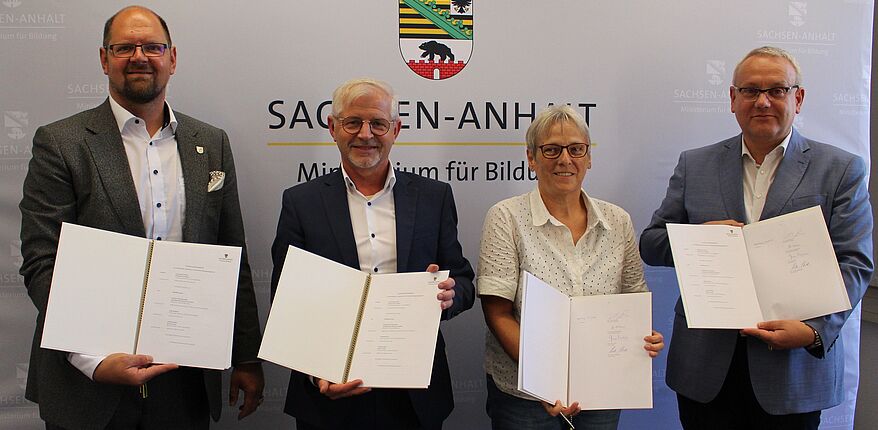 Ministerium für Bildung des Landes Sachsen-Anhalt / v. l. n. r.: Landrat Martin Stichnoth / Staatssekretär Frank Diesener / Katharina Brederlow, Stadt Halle / Landrat Götz Ulrich, Burgenlandkreis. Alle Personen zeigen die unterschriebenen Vereinbarungen. 