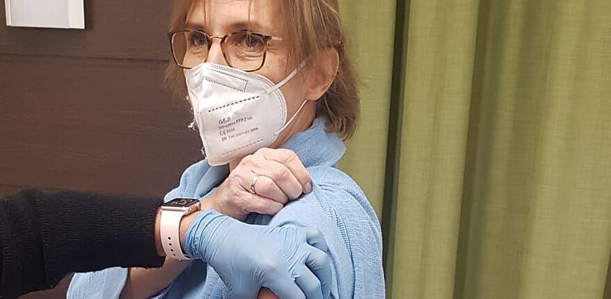 Das Foto zeigt Lehrerin Britta Meyer. Sie fixiert mit einer Hand Ihre Bluse, um sich in den Oberanrm impfen zu lassen.