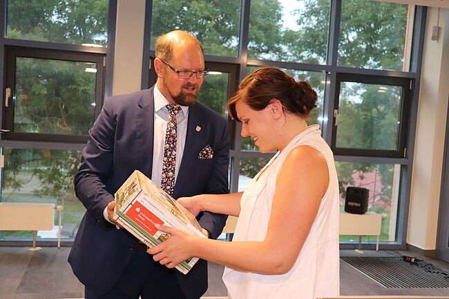 Das Foto zeigt Landrat Martin Stichnoth. Er überreicht der Volksstimmejournalistin Juliane Just eine Börderschatzkiste. 