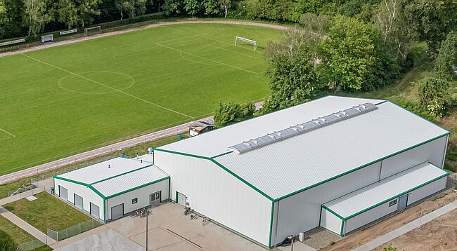 Foto TSV Hadmersleben / auch Landrat Martin Stichnoth war zur Eröffnung da / mehr Fotos über Instagram (Landkreis Börde) verfügbar. auf dem Bild sieht man die Sporthalle aus der Vogelperspektive, dahinter der Außensportplatz.