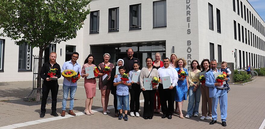 Foto Uwe Baumgart / Landrat Martin Stichnoth hat 16 neuen Staatsbürgern zur offiziellen Einbürgerung gratuliert. Aufstellung zum Erinnerungsfoto vor dem Haupteingang zum Verwaltungsgebäude in Haldensleben. 