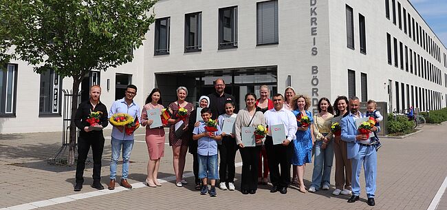 Foto Uwe Baumgart / Landrat Martin Stichnoth hat 16 neuen Staatsbürgern zur offiziellen Einbürgerung gratuliert. Aufstellung zum Erinnerungsfoto vor dem Haupteingang zum Verwaltungsgebäude in Haldensleben. 