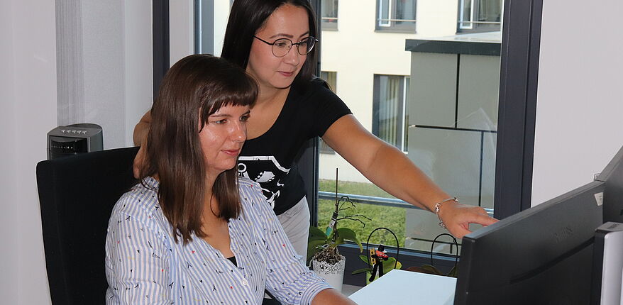 Foto Landkreis Börde / Sophie Heinrich und Franziska Brehmeyer (von links) pflegen die Daten der Trichinenuntersuchungen auf der Internetseite. Beide schauen hier in einen Computerbildschirm.