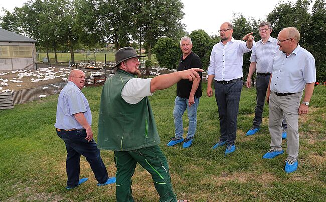 Foto Ottfried Junge / Stippvisite in Wulferstedt, von rechts: Hans Walker, Dr. Wolfgang Nehring, Landrat Martin Stichnoth, Guido Heuer-MdL, Hagen Müller sowie Rüdiger Breier. Die Herren stehen auf einer Wiese am Hang, im Hintergrund ist Geflügel in Freilandhaltung zu sehen.