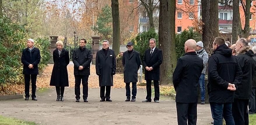 Das Foto zeigt die Teilnehmer der Veranstaltung der Stadt Haldensleben auf dem städtischen Friedhof zum Volkstrauertag. Landrat Martin Stichnoth wird von Dr. Marcus Waselewski vertreten. 