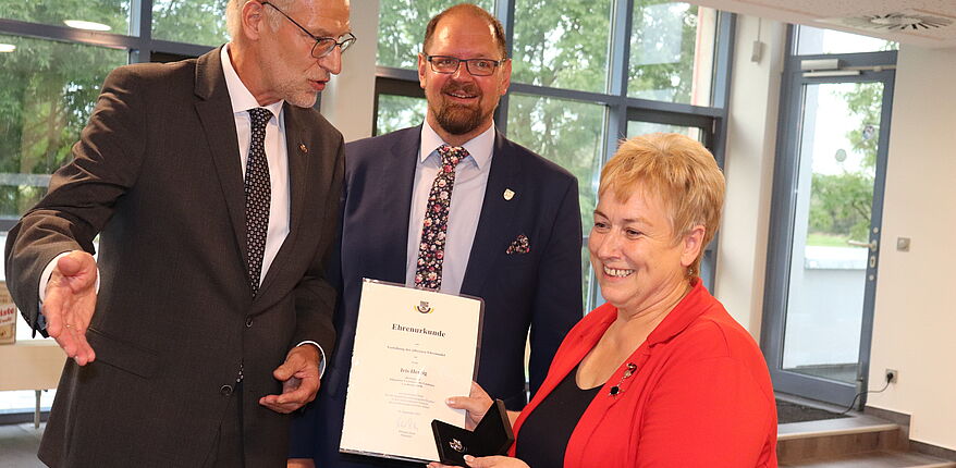 das Foto zeigt Heinz-Lothar Theel und Landrat Martin Stichnoth bei der Auszeichnung. Im Vordergrund Iris Herzig. Sie erhält die Ehrennadel und die dazugehörige Urkunde. Alle Akteure im Bild freuen sich.