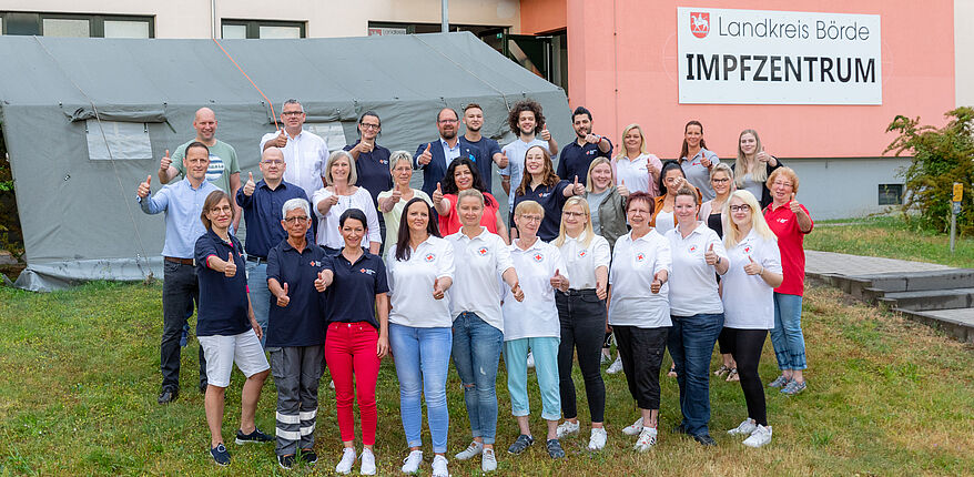 Vor Schließung des Impfzentrums des Landkreises Börde hat das Team in diesen Tagen nochmal Austellung zum Erinnerungsfoto genommen. Das Fotos ist eine Außenaufnahme vor der Fassade des Impfzentrums in Haldensleben auf dem Süplinger Berg. Neben dem Landrat ist das gesamt Team zu sehen. 