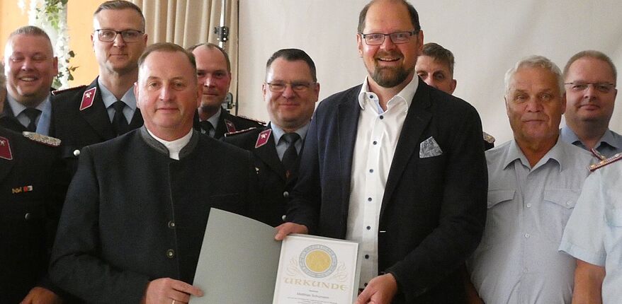 Foto Landkreis Börde / Kreisbrandsmeister Matthias Schumann hat nun den Dienstgrad "Oberbrandinspektor". Im Kreise mehrere Kameraden stehen Schuhmann und Stichnoth mit der Beförderungsurkunde in den Händen in der Mitte.