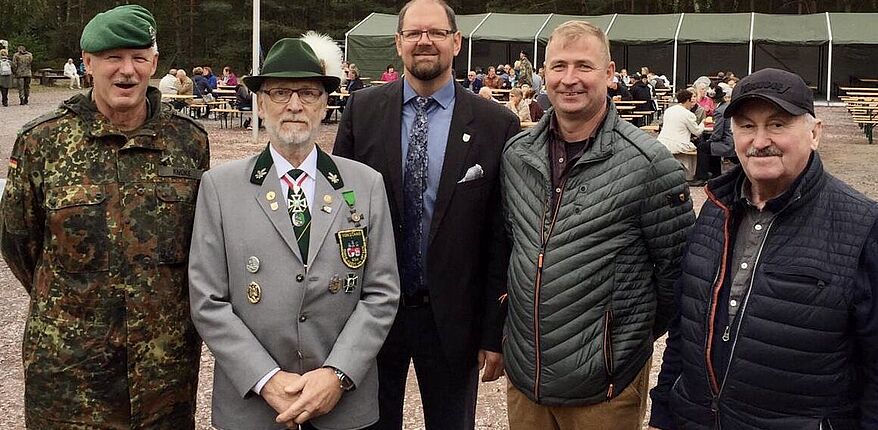 Das Foto zeigt im Vordergrund 5 Personen, darunter Landrat Martin Stichnoth, Kreisschützenmeister Hartmut Neumann und Oberst Michael Knoke, Leiter des Gefechtsübungszentrums des Heeres Letzlingen. Im Hintergrund ist ein Festzelt zu sehen.