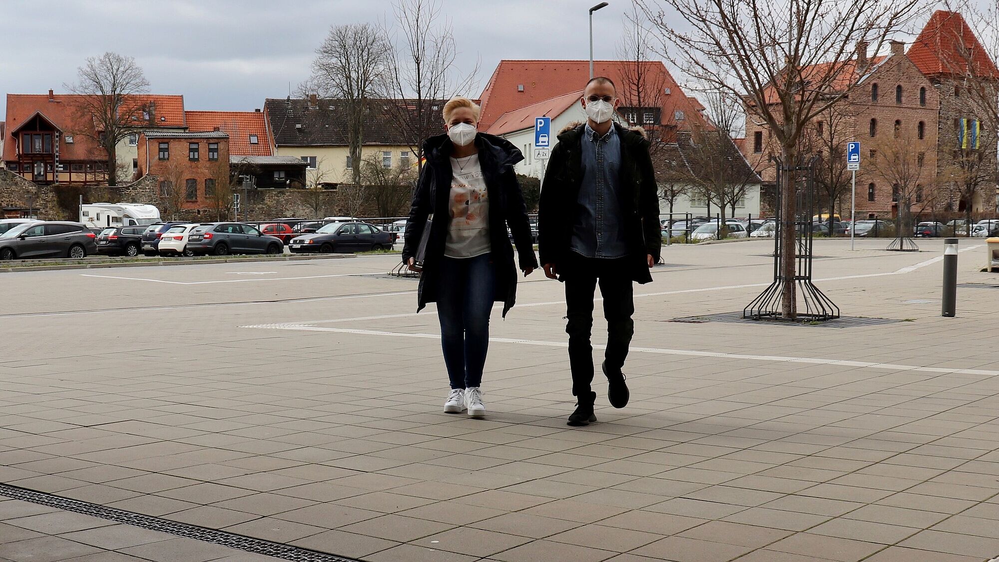 Foto Uwe Baumgart / zunächst bis zum 22. April 2022 bleibt das Tragen einer medizinischen "Mund-Nasen-Bedeckung" für Besucher der Verwaltungsgebäude des Landkreises Börde verpflichtend. Auf dem Foto kommen 2 Besucher mit FFP2-Maske in das Haldensleber Verwaltungsgebäunde. Im Hintergrund sieht man die Stadt mit Kirchturm und Stendaler Torturm. 