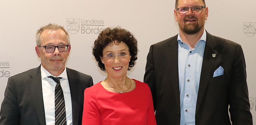 Foto Uwe Baumgart / Landrat Martin Stichnoth und Beigeordneter Peter Weiß (Landkreistag Sachsen-Anhalt) ehren Petra Naumann mit der silbernen Ehrennadel des Landkreistages von Sachsen-Anhalt. Die beiden Herren nehmen Petra Naumann in die Mitte.